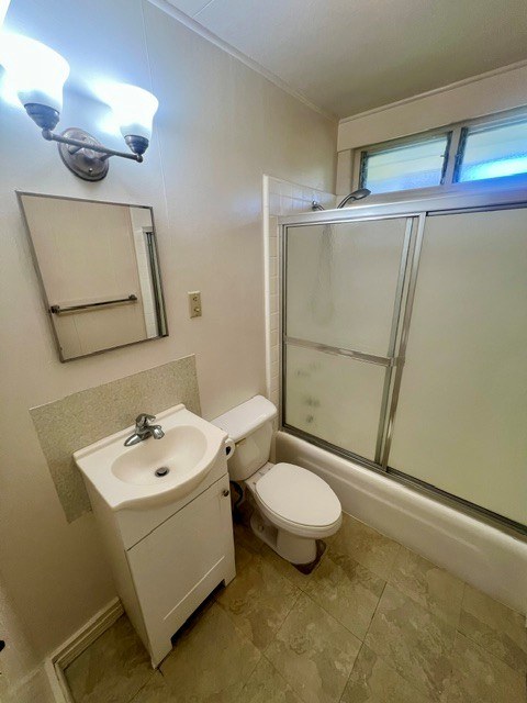 A small bathroom with a toilet, sink, and mirror.